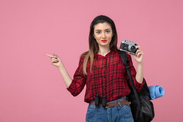 Vista frontal mujer joven tomando fotografías con cámara en el modelo de foto de mujer de fondo rosa