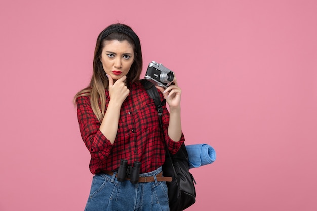 Vista frontal mujer joven tomando fotografías con cámara en el modelo de foto de mujer de fondo rosa