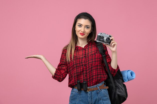 Vista frontal mujer joven tomando fotografías con cámara en el modelo de foto de mujer de fondo rosa