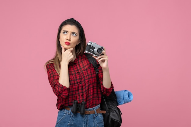 Vista frontal mujer joven tomando fotografías con cámara sobre fondo rosa claro color de fotografía de mujer