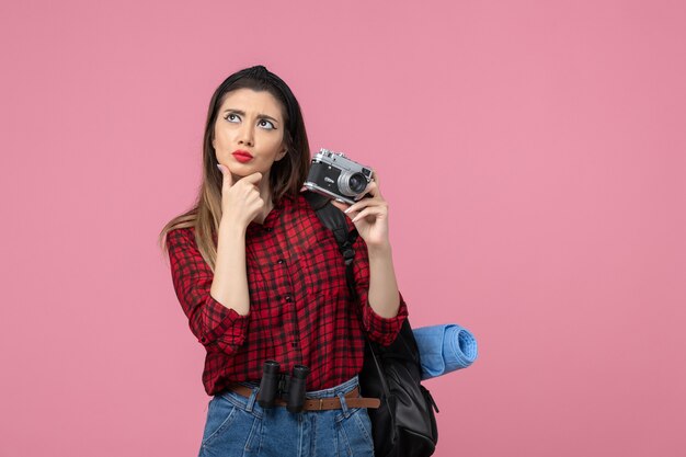 Vista frontal mujer joven tomando fotografías con cámara sobre fondo rosa claro color de fotografía de mujer