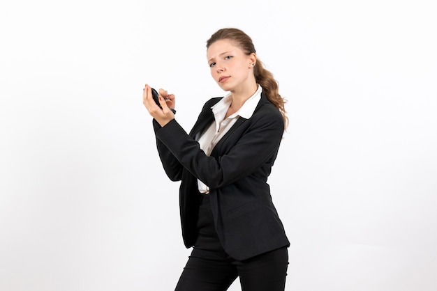 Vista frontal mujer joven en traje clásico estricto haciendo maquillaje sobre fondo blanco modelo mujer trabajo serio traje de negocios