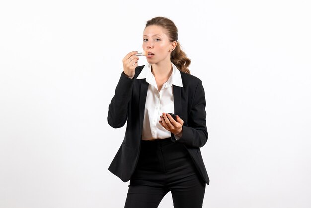 Vista frontal mujer joven en traje clásico estricto haciendo su maquillaje en el escritorio blanco mujer trabajo traje negocio trabajo femenino