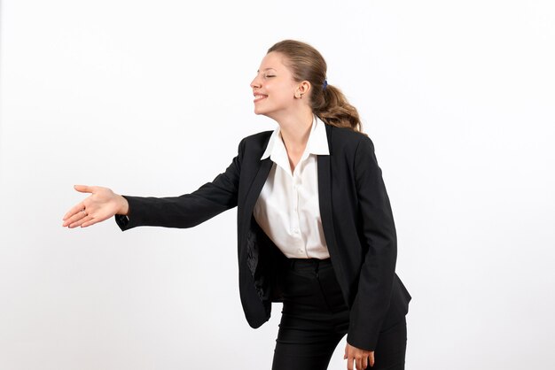 Vista frontal mujer joven en traje clásico estricto saludando a alguien en el escritorio blanco mujer de negocios trabajo traje de trabajo femenino