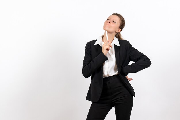 Vista frontal mujer joven en traje clásico estricto sosteniendo la pluma y pensando sobre fondo blanco trabajo de mujer traje de trabajo femenino de negocios