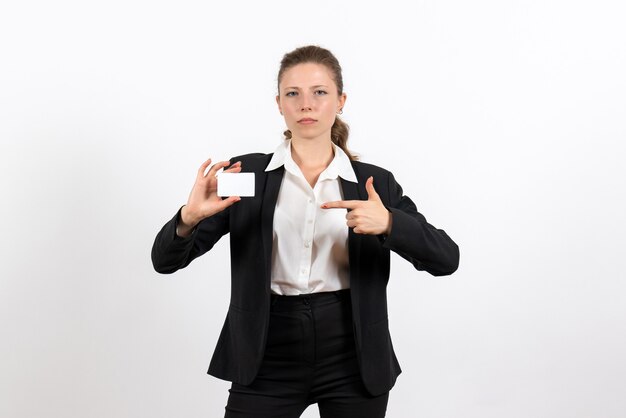 Vista frontal mujer joven en traje clásico estricto sosteniendo una tarjeta blanca en el escritorio blanco trabajo mujer trabajo mujer traje mujer