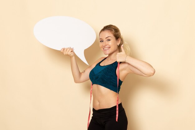 Vista frontal mujer joven en traje de deporte con cartel blanco