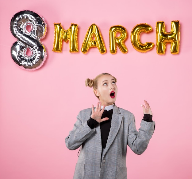 Foto gratuita vista frontal mujer joven en traje gris con decoración de marzo en color de fondo rosa presente fiesta de igualdad de vacaciones del día de la mujer sensual horizontal