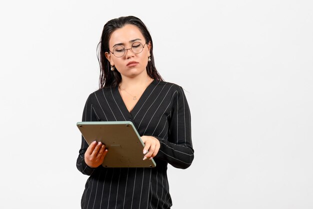 Vista frontal mujer joven en traje oscuro estricto trabajando con enorme calculadora sobre fondo blanco trabajo mujer dama belleza moda negocio