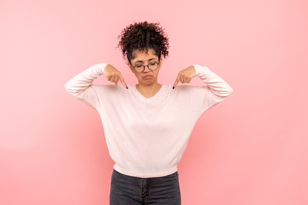 Vista frontal de la mujer joven triste en la pared rosa