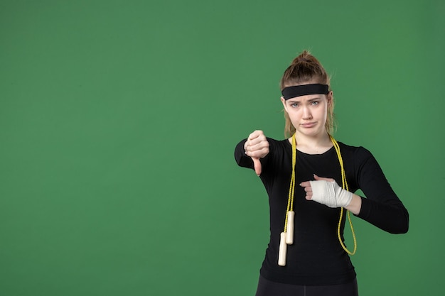 Vista frontal mujer joven con vendaje alrededor de su brazo herido sobre fondo verde atleta dolor salud lesión hospital mujer deporte entrenamiento