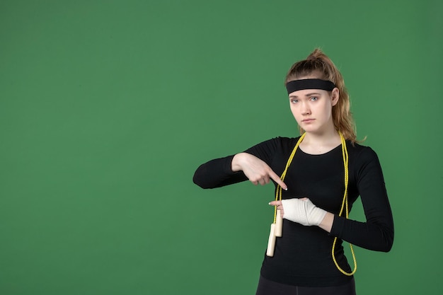 Foto gratuita vista frontal mujer joven con vendaje alrededor de su brazo herido sobre fondo verde atleta entrenamiento flex salud mujer lesión deporte cuerpo hospital