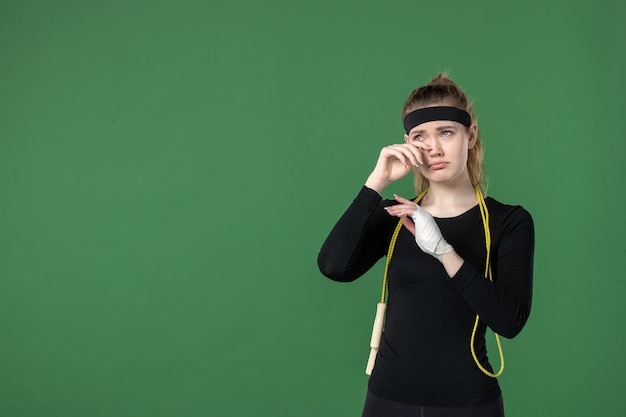 Vista frontal mujer joven con vendaje alrededor de su brazo herido sobre fondo verde atleta entrenamiento salud lesión deporte cuerpo hospital mujer