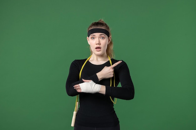 Vista frontal mujer joven con vendaje alrededor de su brazo herido sobre fondo verde deporte atleta dolor mujer entrenamiento color corporal lesión salud