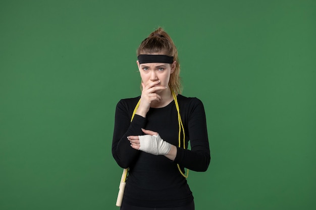 Vista frontal mujer joven con vendaje alrededor de su brazo herido sobre fondo verde deporte atleta dolor salud mujer entrenamiento color corporal lesión