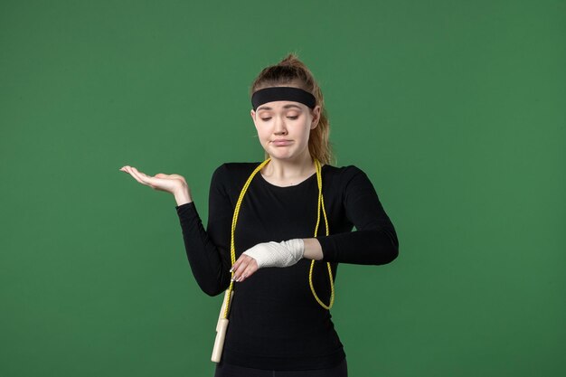 Foto gratuita vista frontal mujer joven con vendaje alrededor de su brazo herido sobre fondo verde deporte atleta dolor salud mujer entrenamiento color lesión