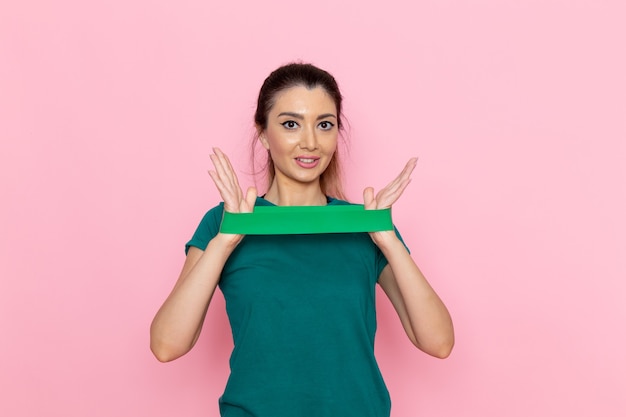 Foto gratuita vista frontal mujer joven con vendaje verde en la pared rosada belleza deporte ejercicio atleta entrenamiento delgado