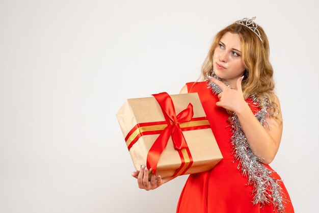 Vista frontal mujer joven en vestido rojo con regalo de Navidad