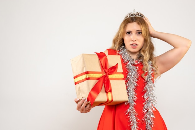 Vista frontal mujer joven en vestido rojo con regalo de Navidad