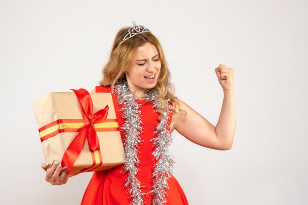 Vista frontal mujer joven en vestido rojo con regalo de Navidad