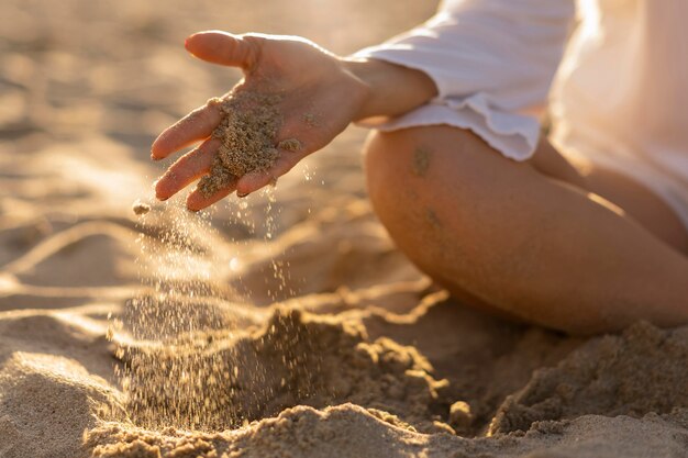 Vista frontal de la mujer jugando con arena de playa