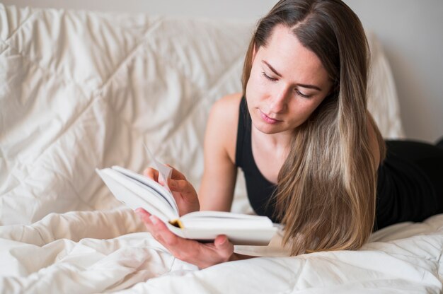 Vista frontal de la mujer leyendo en la cama