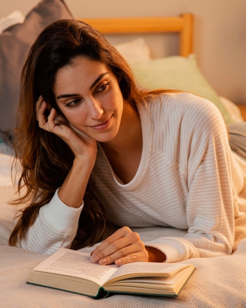 Foto gratuita vista frontal de la mujer leyendo un libro en casa