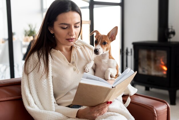 Vista frontal de la mujer leyendo mientras sostiene a su perro