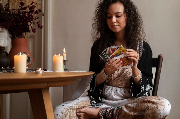 Vista frontal mujer leyendo tarot en casa