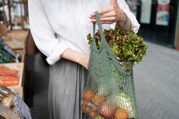 Vista frontal mujer llevando comestibles en bolso de mano