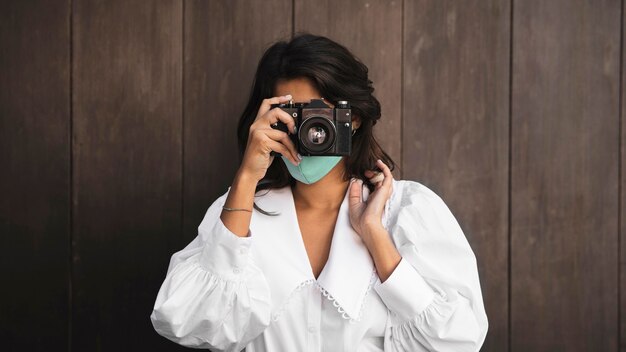 Foto gratuita vista frontal de la mujer con mascarilla con cámara