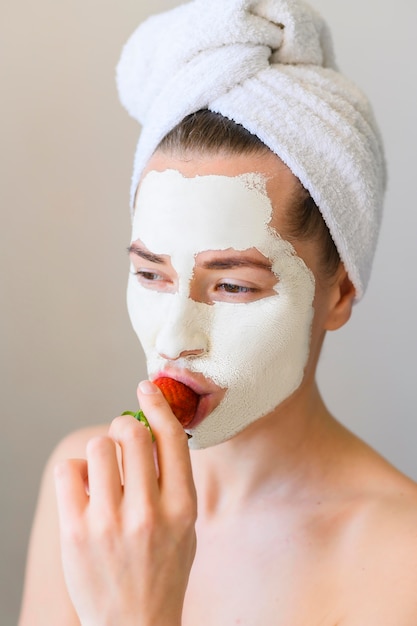 Vista frontal de la mujer con mascarilla comiendo fresa