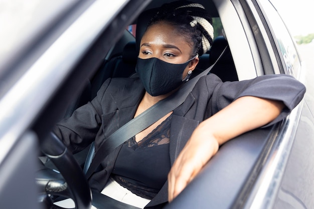 Foto gratuita vista frontal de la mujer con mascarilla conduciendo su coche