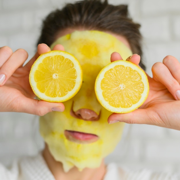 Vista frontal de la mujer con mascarilla con rodajas de limón