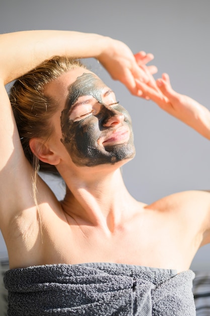 Vista frontal de la mujer con mascarilla tomando el sol en casa