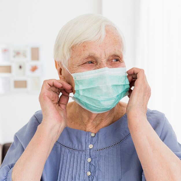 Vista frontal de una mujer mayor posando con máscara médica