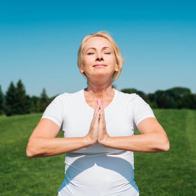 Foto gratuita vista frontal mujer meditando al aire libre