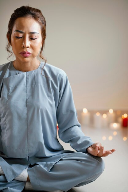 Vista frontal de la mujer meditando junto a velas con espacio de copia