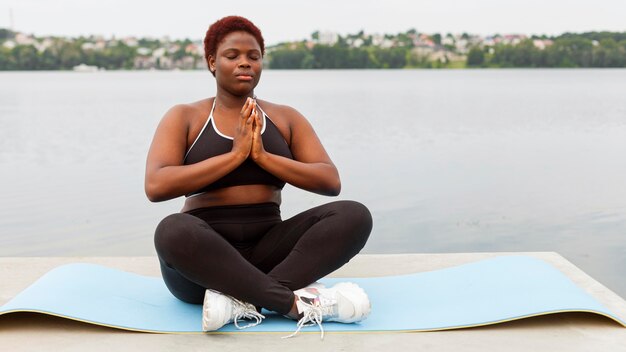 Vista frontal de la mujer meditando en la playa