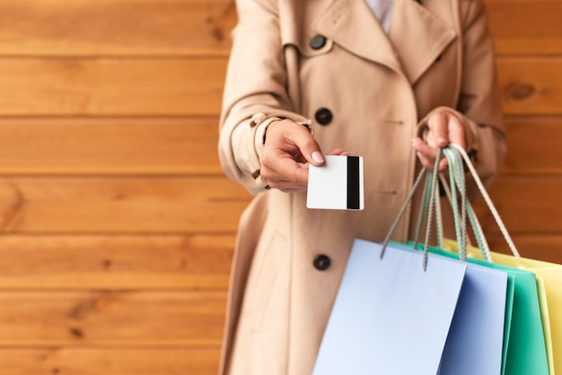 Vista frontal de la mujer con un montón de bolsas de la compra que le ofrece su tarjeta de crédito