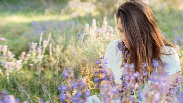 Vista frontal de la mujer en la naturaleza admirando flores