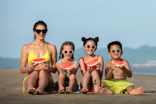 Vista frontal mujer y niños en la playa