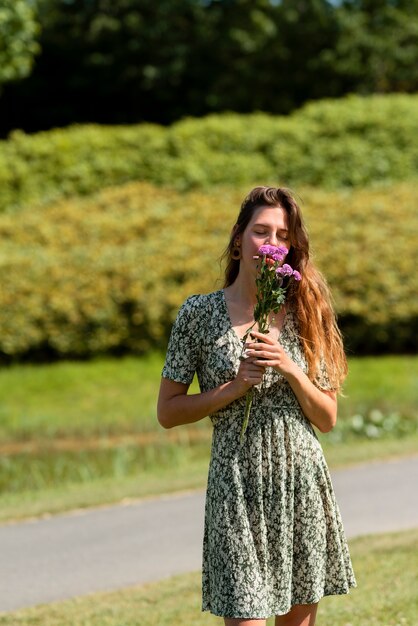 Vista frontal mujer oliendo flores