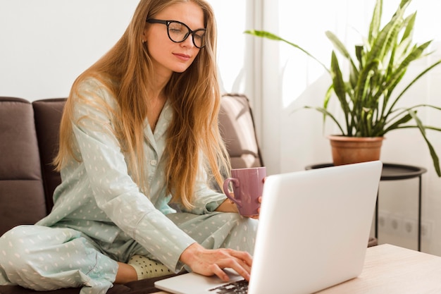 Vista frontal de la mujer en pijama en casa trabajando