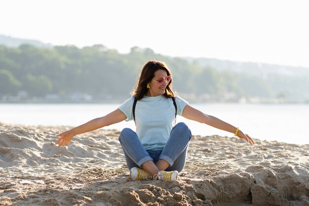 Vista frontal de la mujer en la playa disfrutando de arena