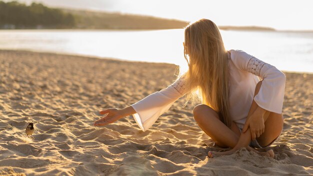 Vista frontal de la mujer en la playa con pájaro