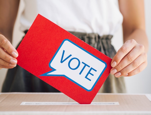 Vista frontal mujer poniendo un mensaje de votación en un cuadro