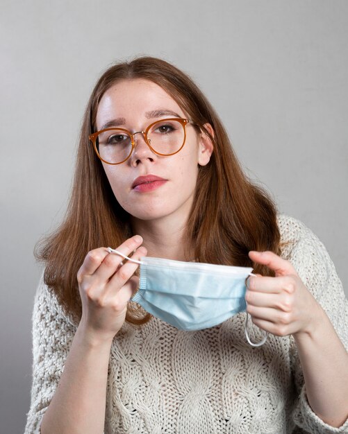 Vista frontal de la mujer poniéndose una máscara médica para protección