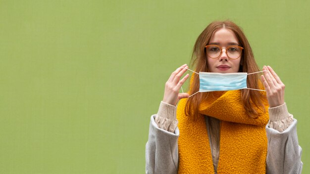 Vista frontal de la mujer poniéndose mascarilla médica con espacio de copia