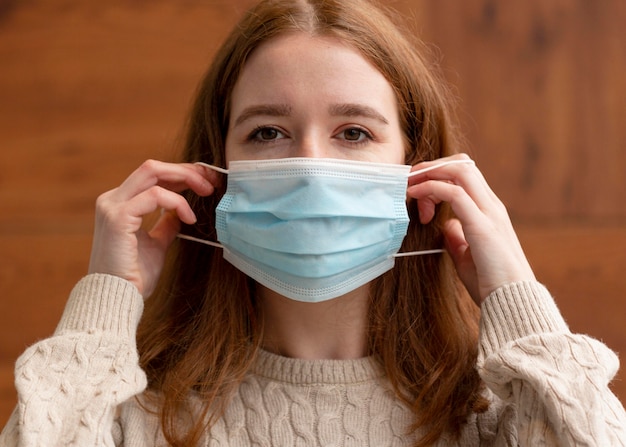 Foto gratuita vista frontal de la mujer poniéndose mascarilla médica